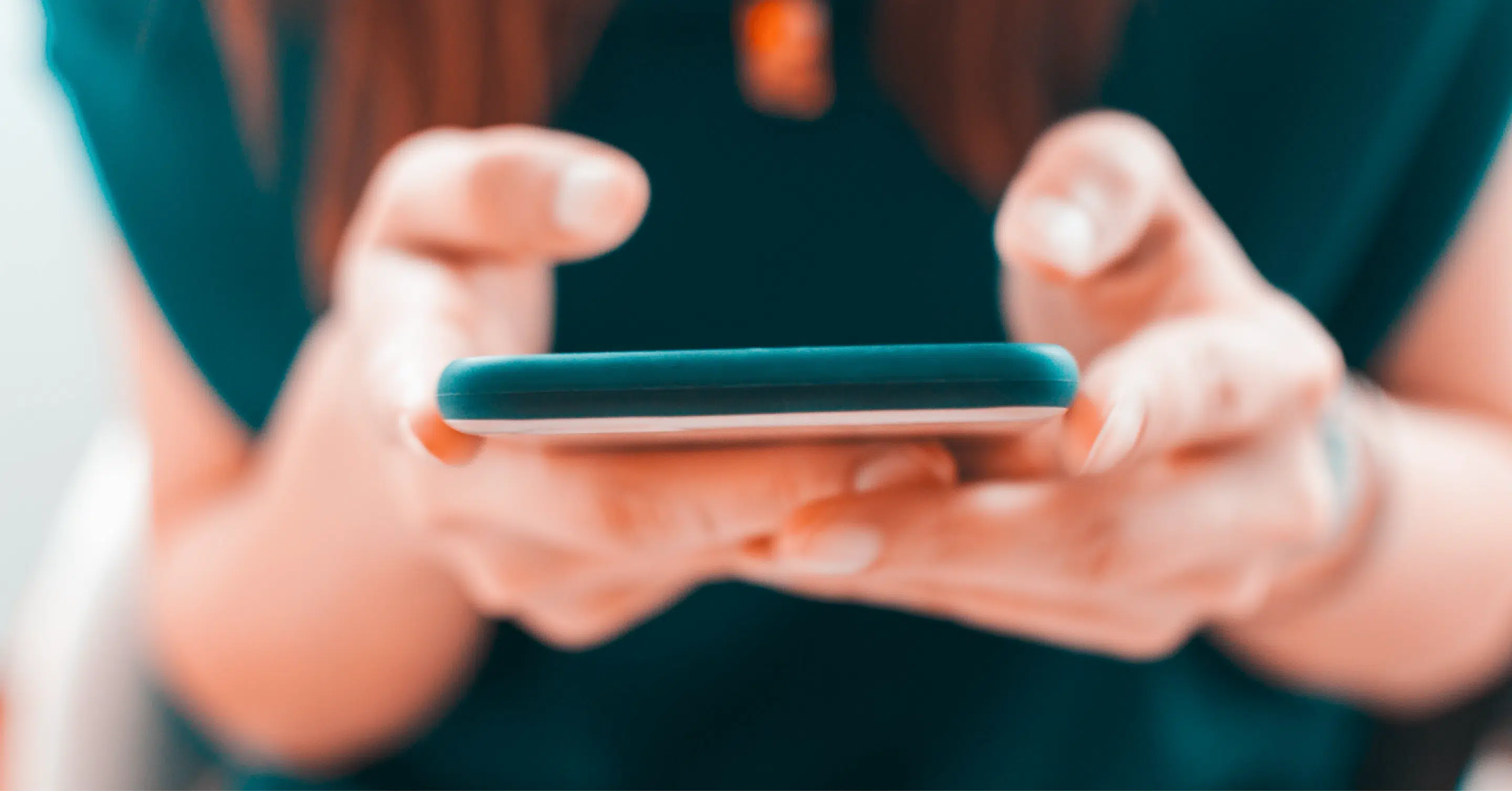 A close-up, horizontal view of a person’s hands holding and using a smartphone.
