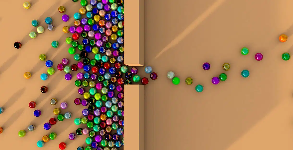 Colorful Marbles entering through a small wooden opening.