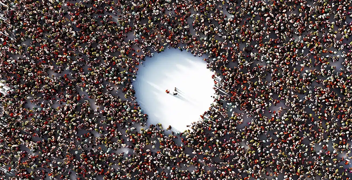 A massive crowd seen from above with a circle cleared in the center with a few people in it.