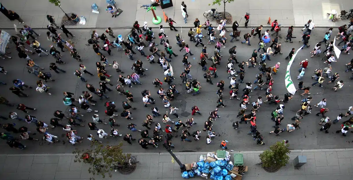 BGM21 264997 GenZ Perspectives High-angle aerial view of a large crowd walking down a city street.