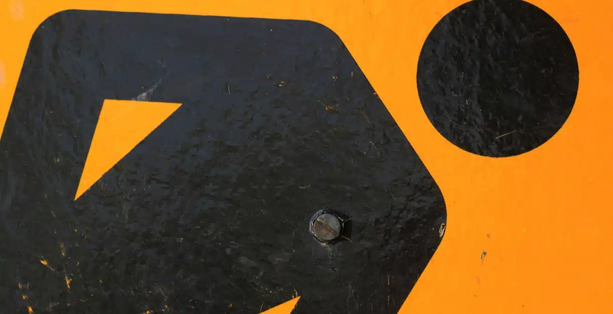 BGM21 367595 Infrastructure Macro shot of a black graphic symbol of a person on an orange construction sign with a visible mounting bolt.
