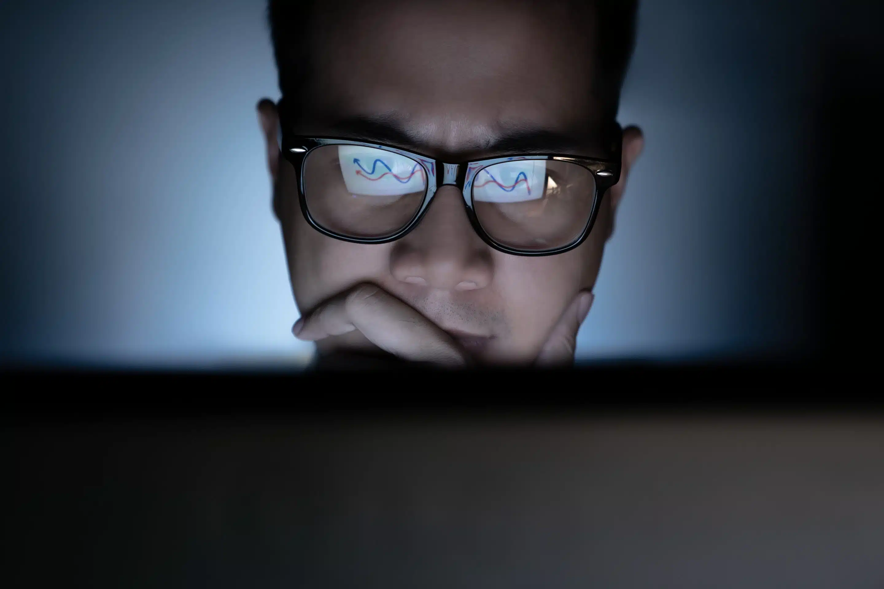 A man focused on a computer in the dark.