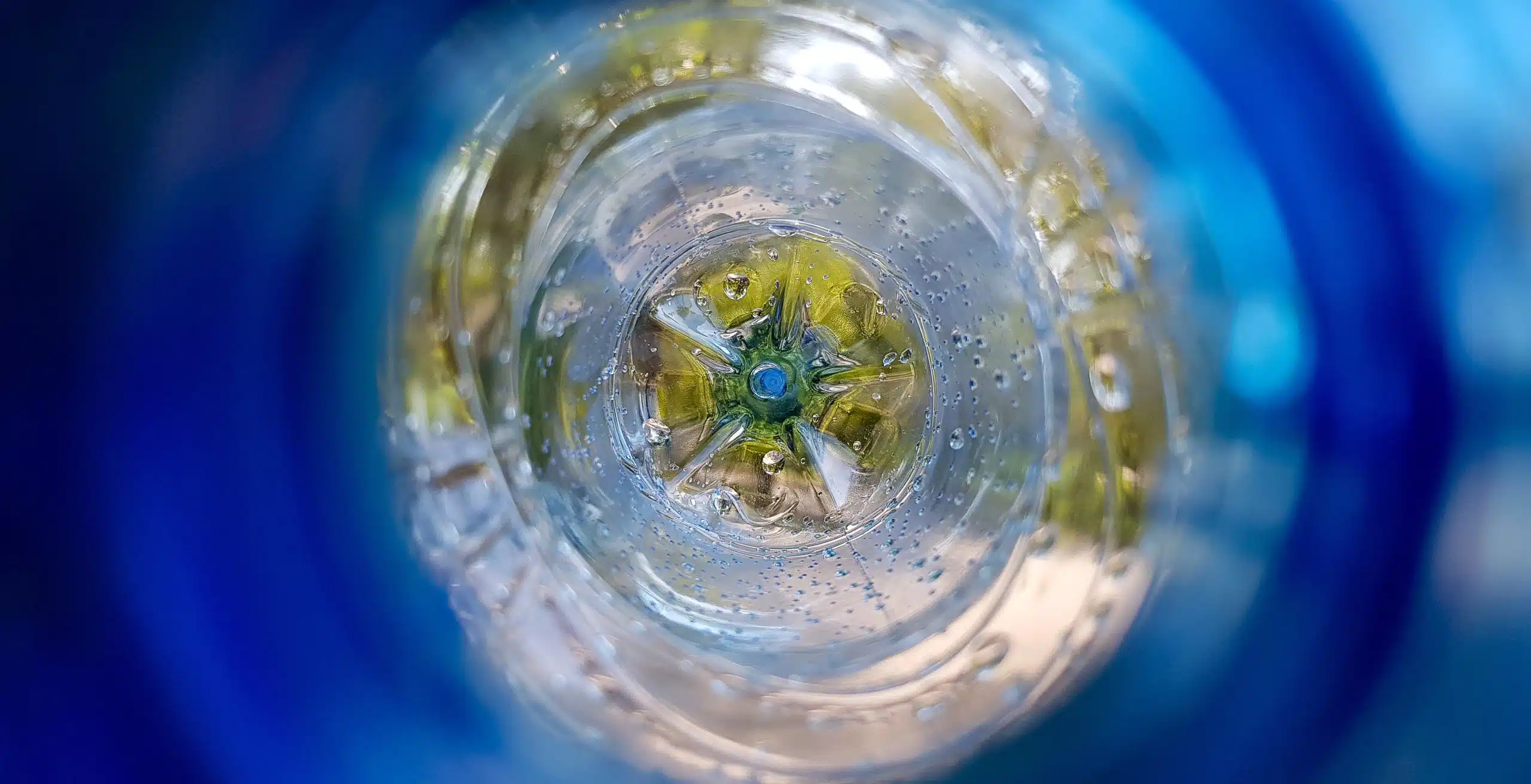 Long background with a plastic blue bottle with water drops inside