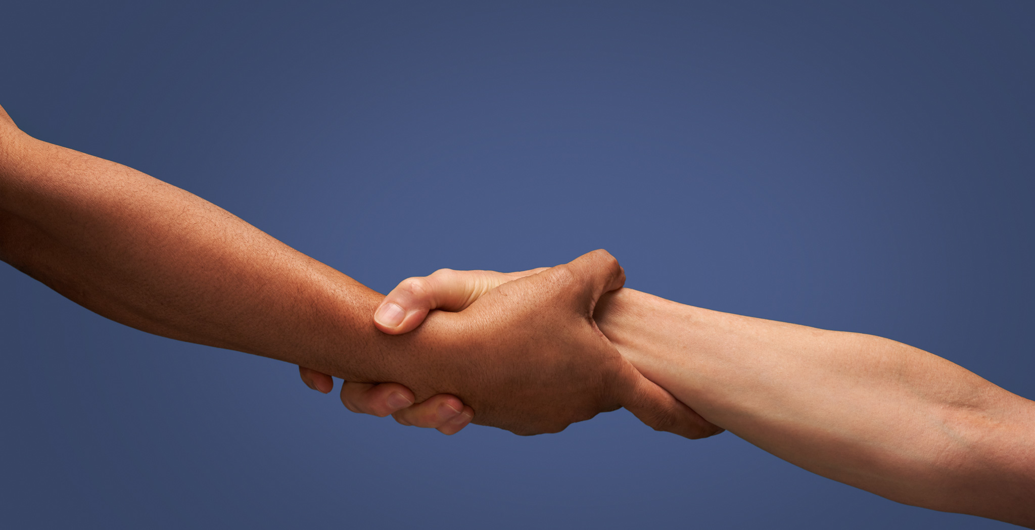 Close up of holding hands A close-up of two people holding each other's hands against a solid blue background.