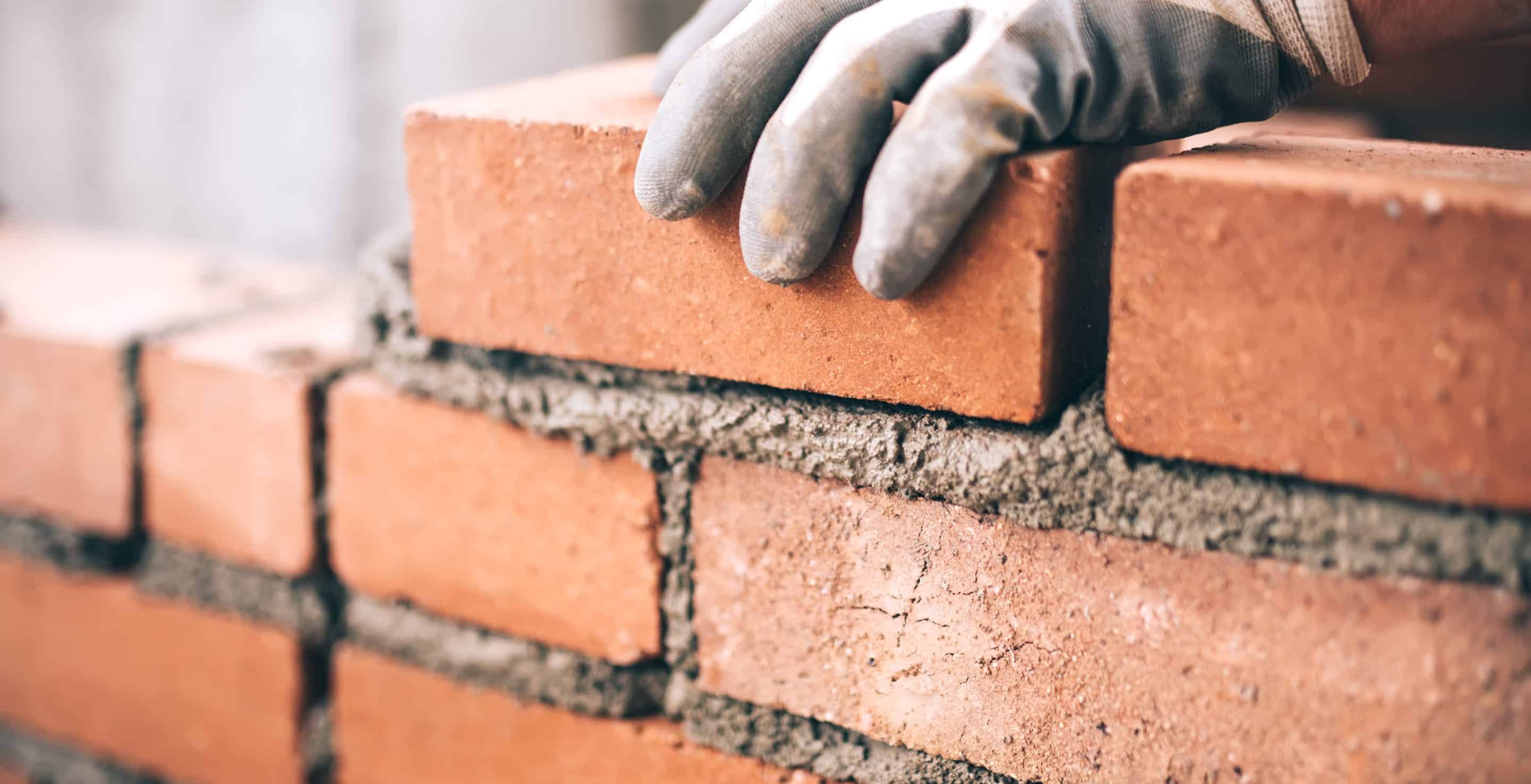Close up of industrial bricklayer installing bricks on construction site Close up of industrial bricklayer installing bricks on construction site
